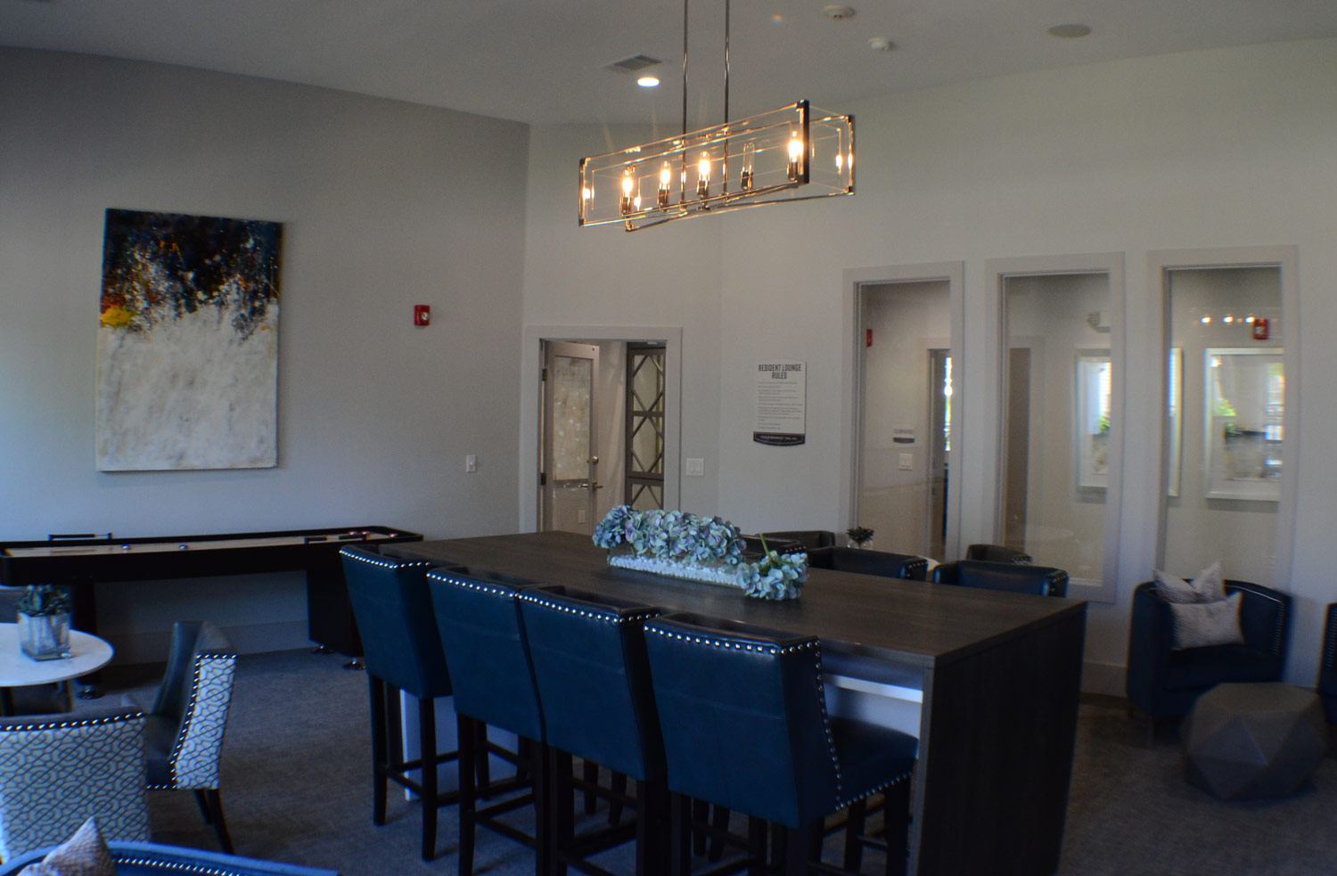 Renovated apartment clubroom with a long dining table and pendant light